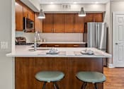 Thumbnail 18 of 30 - A kitchen with a white countertop and wooden cabinets.