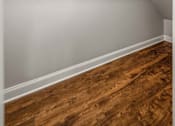 Thumbnail 21 of 30 - Empty room with a white wall and a wooden floor.