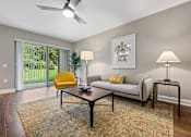 Thumbnail 7 of 30 - A living room with a yellow chair, a white couch, and a patterned rug.