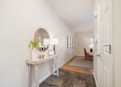 Thumbnail 6 of 45 - A hallway with a white door and a table with a plant on it.