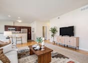 Thumbnail 5 of 45 - A living room with a white couch, a wooden coffee table, and a television.