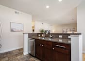 Thumbnail 21 of 45 - A kitchen with a white counter top and brown cabinets.