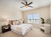 Thumbnail 24 of 45 - A bedroom with a bed, chair, and ceiling fan.