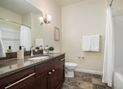 Thumbnail 16 of 45 - A bathroom with a toilet, sink, and a shower curtain.