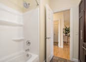 Thumbnail 43 of 45 - A white bathroom with a white tub and a white door.