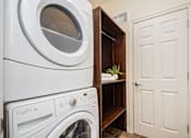 Thumbnail 25 of 45 - A white washing machine and dryer in a small laundry room.