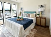 Thumbnail 19 of 28 - A bedroom with a bed, a ceiling fan, and a window overlooking a parking lot.