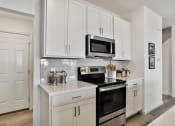 Thumbnail 9 of 33 - a kitchen with white cabinets and a stove and a microwave at The Prairie Villas, Missouri, 63368