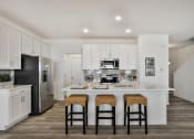 Thumbnail 7 of 33 - a kitchen with a large island with three stools at The Prairie Villas, Missouri