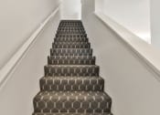 Thumbnail 10 of 33 - a flight of stairs with a black and white carpeted stair case and white walls at The Prairie Villas, Missouri, 63368