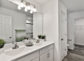 Thumbnail 17 of 33 - a bathroom with a large mirror and a white sink at The Prairie Villas, Dardenne Prairie