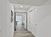 Thumbnail 21 of 33 - a long white hallway with white doors and a door to a bathroom at The Prairie Villas, Dardenne Prairie, MO