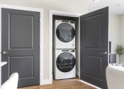 Thumbnail 23 of 28 - a white washer and dryer in a room with black doors at The Junction at Rogers, Rogers