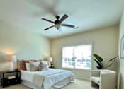 Thumbnail 27 of 45 - A bedroom with a bed, a chair, and a ceiling fan.