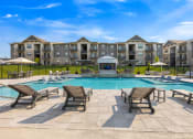 Thumbnail 32 of 33 - spacious pool deck with lounge chairs and sparkling pool with The Prairie Luxury Apartments in the background at The Prairie Villas, Missouri, 63368