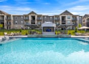 Thumbnail 30 of 33 - a swimming pool with lounge chairs and umbrellas in front of an apartment building at The Prairie Villas, Dardenne Prairie, MO 63368