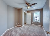 Thumbnail 8 of 32 - A room with a ceiling fan and carpeted floor.
