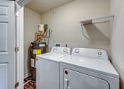 Thumbnail 13 of 32 - A white washer and dryer in a small laundry room.