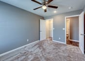 Thumbnail 17 of 32 - A room with a ceiling fan and carpeted floor.