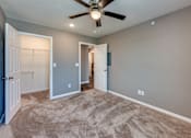 Thumbnail 18 of 32 - A room with a ceiling fan and carpeted floor.