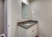 Thumbnail 20 of 32 - A bathroom with a granite countertop and white cabinets.