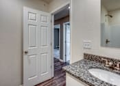 Thumbnail 29 of 32 - A white door is in a bathroom with a granite counter top.