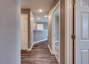 Thumbnail 27 of 32 - A hallway with a white door on the right and a brown door on the left.