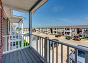 Thumbnail 26 of 32 - A balcony overlooks a parking lot and apartment buildings.