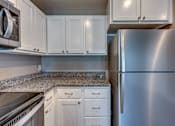 Thumbnail 25 of 32 - A kitchen with a stainless steel refrigerator and white cabinets.