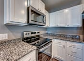 Thumbnail 22 of 32 - A kitchen with granite countertops and white cabinets.