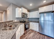 Thumbnail 21 of 32 - A modern kitchen with white cabinets and stainless steel appliances.