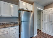 Thumbnail 3 of 32 - A kitchen with a refrigerator, cabinets, and a doorway leading to another room.