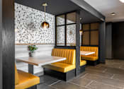 Thumbnail 29 of 46 - A restaurant interior with a white table and yellow booths.