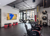 Thumbnail 31 of 46 - A gym with a row of stationary bikes and a painting on the wall.