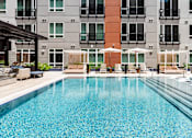 Thumbnail 16 of 46 - A large swimming pool in front of a multi-story apartment building.