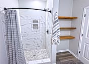 Thumbnail 16 of 18 - A bathroom with a marble tile shower and a towel hanging on a rack.