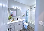Thumbnail 9 of 18 - A white bathroom with a toilet, sink, and mirror.