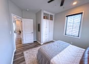 Thumbnail 6 of 18 - A bedroom with a bed, dresser, and a ceiling fan.