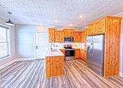 Thumbnail 10 of 18 - A kitchen with wooden cabinets and a refrigerator.