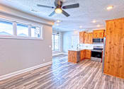 Thumbnail 14 of 18 - A kitchen with wooden cabinets and a ceiling fan.