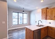 Thumbnail 15 of 18 - A kitchen with wooden cabinets and a stainless steel dishwasher.