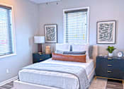 Thumbnail 5 of 18 - A bedroom with a bed, nightstand, and two framed pictures on the wall.