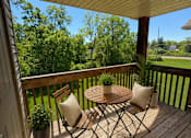 Thumbnail 12 of 19 - A wooden deck with a table and chairs overlooking a lush green yard.