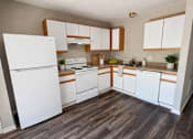 Thumbnail 3 of 19 - A kitchen with white appliances and wooden floors.