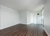 Thumbnail 11 of 42 - an empty living room with white walls and wood flooring at Clayton On The Park, Clayton, MO