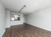 Thumbnail 13 of 42 - an empty living room with wood flooring and a kitchen at Clayton On The Park, Missouri