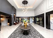 Thumbnail 19 of 36 - A large, elegant foyer with a marble floor and a chandelier at The Cunningham Apartments, Iowa