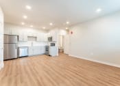 Thumbnail 2 of 18 - living room with open floorplan and modern kitchen with white cabinets, stainless steel appliances and plank vinyl flooring at Pure Lowell, Lowell, AR