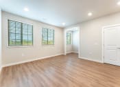 Thumbnail 3 of 18 - living room with can lighting, large windows and vinyl plank flooring at Pure Lowell, Lowell, AR 72745