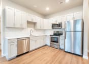 Thumbnail 1 of 18 - modern kitchen with white cabinets, stainless steel appliances and plank vinyl flooring at Pure Lowell, Arkansas, 72745